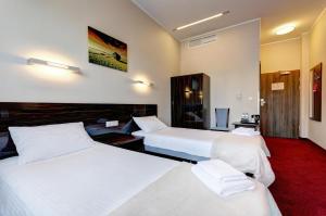 a hotel room with two beds and a red carpet at Focus Hotel Gdańsk in Gdańsk