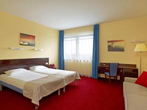 a hotel room with two beds and a desk and a table at Focus Hotel Gdańsk in Gdańsk