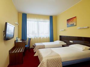 a hotel room with two beds and a flat screen tv at Focus Hotel Gdańsk in Gdańsk