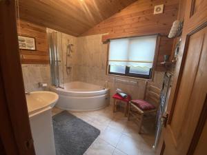 ein Badezimmer mit einer Badewanne, einem WC und einem Waschbecken in der Unterkunft Cozy Cabin with Stunning Loch Lomond Views in Rowardennan