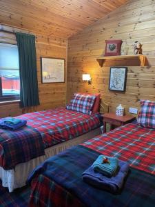 a bedroom with two beds in a log cabin at Cozy Cabin with Stunning Loch Lomond Views in Rowardennan