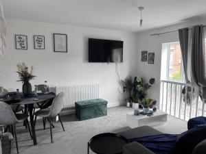 a living room with a table and a television on the wall at Birmingham City 2 Bedroom Apartment in Birmingham