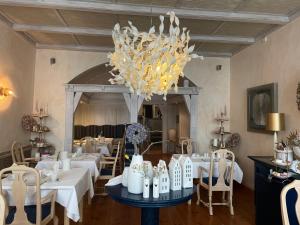 uma sala de jantar com mesas brancas e um lustre em Haus Wullfcrona em Stralsund