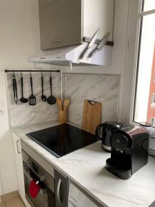 - une cuisine avec un comptoir, une cuisinière et des ustensiles dans l'établissement Charmant appartement cosy 2 pièces Paris 15e, à Paris