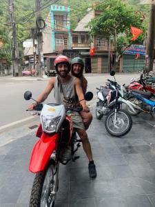 Un uomo e una donna seduti su una moto rossa di Ngan Ha Homestay a Ha Giang