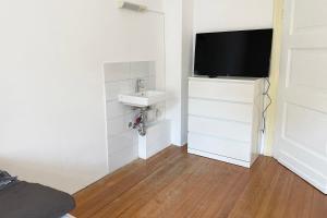 Cette petite chambre blanche dispose d'un lavabo et d'une télévision. dans l'établissement Apartment with balcony in Edingen-Neckarhausen, à Edingen-Neckarhausen