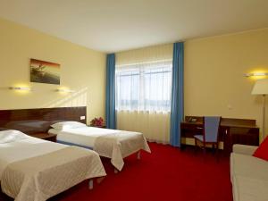 a hotel room with two beds and a desk at Focus Hotel Gdańsk in Gdańsk