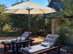 twee stoelen en een tafel met een paraplu op een terras bij The Dreamcatcher Lodge in Hoedspruit