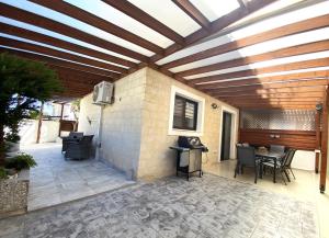 un patio con techo de madera, mesa y sillas en Kyklades Resort & Spa, en Paralimni