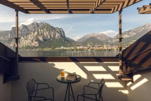 a balcony with a table and chairs and mountains at Hotel Promessi Sposi in Malgrate