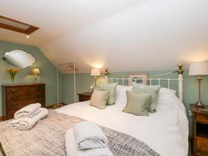 Little Stables Cottage في بلاندفورد فوروم: غرفة نوم بسرير كبير عليها شراشف ووسائد بيضاء