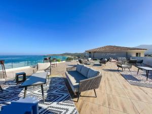 un patio con sillas, mesas y el océano en Eco-Résidence Dolce Paese, en Algajola