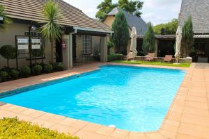 a large blue swimming pool in front of a house at Scott's Manor Guesthouse Function and Conference Venue in Lichtenburg
