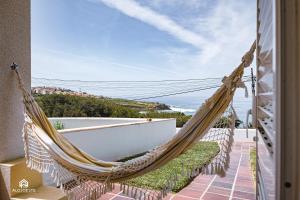 uma rede de descanso numa varanda com vista para o oceano em Villa Castelo de Mar na Ericeira