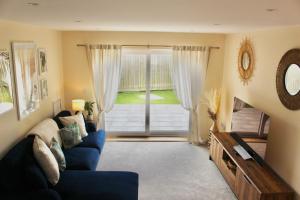 a living room with a blue couch and a sliding glass door at No 1 The Paddock in Bude