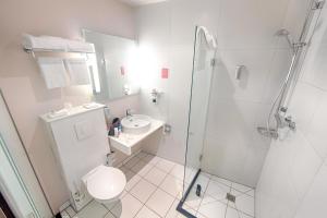 a bathroom with a shower and a toilet and a sink at Leonardo Hotel Utrecht City Center in Utrecht