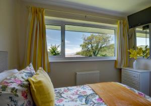 a bedroom with a bed and a large window at Bay View Bungalow in Combe Martin