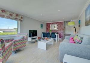 a living room with a couch and chairs and a tv at Bay View Bungalow in Combe Martin