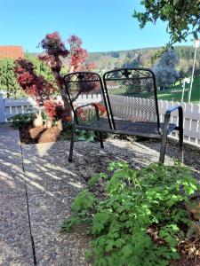 a black bench sitting in the middle of a garden at Ferienwohnung Haus Sommerberg in Leonhardshof