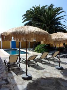 een groep stoelen en parasols naast een zwembad bij Apartamentos Casa Rosán, junto a la Caldera de Taburiente in El Paso
