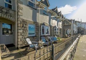 a group of chairs sitting on a fence next to a building at Seaview Moorings in Porthleven