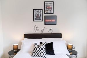 a bedroom with a white bed with four pictures on the wall at Opulent 2 Bedroom City Centre Apartment in Nottingham