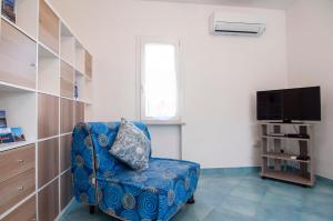 sala de estar con silla azul y TV en Circeo Holiday Houses en San Felice Circeo