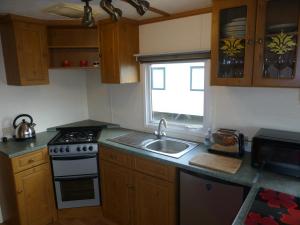 a kitchen with a sink and a stove and a window at 73 Port Haverigg in Millom