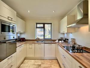 a kitchen with white cabinets and a sink at Beacon Cottage by Inspire Stays in Ditchling