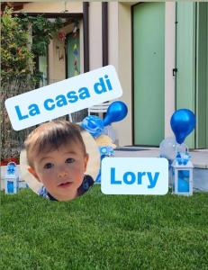 Un niño pequeño en la hierba con un cartel que dice la casa dh en La casa di Lory, en Cessalto