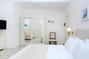 una camera bianca con un grande letto e uno specchio di Hotel Syrene a Capri