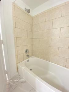 a white bath tub in a bathroom with tiles at Lovely Remodeled 2bdrm Basement Home in Washington, D.C.