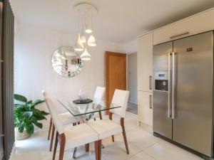 a kitchen and dining room with a glass table and white chairs at Lavender Lodge in Coalville