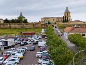 a parking lot filled with cars in front of a castle at Hospedería Puerta de la Catedral in Ciudad-Rodrigo