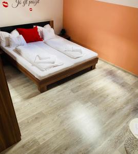 R-Andi fészek في بودابست: غرفة نوم بسرير ذو شراشف بيضاء ومخدات حمراء