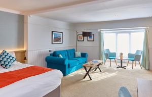a hotel room with a bed and a blue couch at Trearddur Bay Hotel in Trearddur