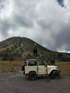 Un homme debout au sommet d'une jeep devant une colline dans l'établissement Ecobromo, à Pasuruan