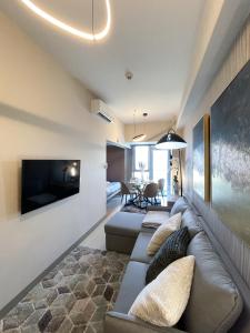 ein Wohnzimmer mit einem Sofa und einem Flachbild-TV in der Unterkunft Amazing Unit and View in Uptown Parksuites BGC in Manila