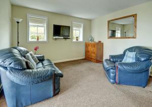 a living room with two blue leather chairs and a mirror at Cedars Lodge in Northam