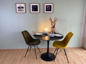 une table avec trois chaises et une table avec une bougie dans l'établissement Apartment Lahnblick, à Marbourg