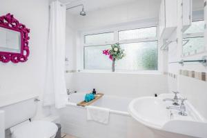 a white bathroom with a sink and a toilet and a window at Stylish Victorian 3 Bed House Huge Garden/Parking in Staines +19 photos