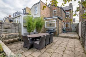 a patio with a table and chairs in front of a house at Stylish Victorian 3 Bed House Huge Garden/Parking in Staines