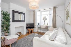 a living room with a white couch and a tv at Stylish Victorian 3 Bed House Huge Garden/Parking in Staines