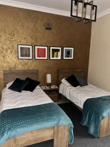 two beds in a room with pictures on the wall at Desert Rose Quiet house 3km away from airport in Safi