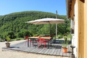 eine Terrasse mit einem Tisch, Stühlen und einem Sonnenschirm in der Unterkunft Oltarcie - Maison d'hôte avec piscine in Espagnac-Sainte-Eulalie