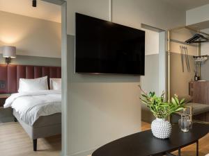 韋克舍的住宿－韋克舍城鎮精英酒店，一间卧室配有一张床,墙上配有电视