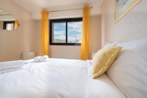 Schlafzimmer mit einem weißen Bett und einem Fenster in der Unterkunft LE LONG BEACH Appartement pour 4 By Sunset Riviera Holidays in Juan-les-Pins