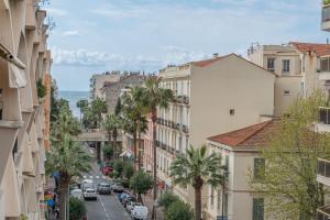 eine Stadtstraße mit Palmen und Gebäuden in der Unterkunft LE LONG BEACH Appartement pour 4 By Sunset Riviera Holidays in Juan-les-Pins