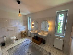 a bathroom with two sinks and a toilet and a mirror at Alter Südhof in Borstel