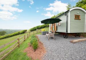 a green tiny house with a bench and an umbrella at The Cloud in Bampton